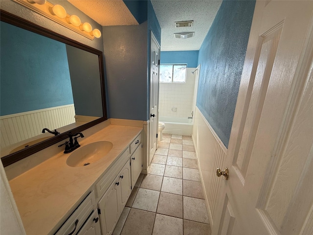 full bathroom featuring vanity, a textured ceiling, tile patterned floors, toilet, and tiled shower / bath