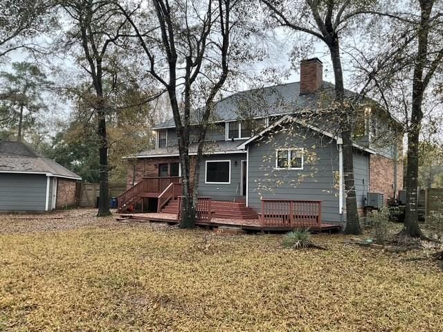 rear view of property featuring central AC unit, an outbuilding, a deck, and a lawn