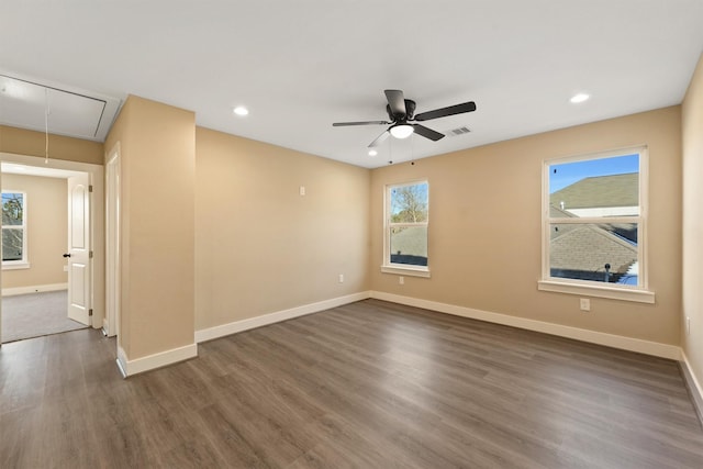 spare room featuring dark wood-type flooring, plenty of natural light, and ceiling fan