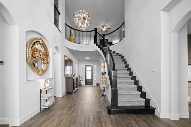 foyer entrance with dark hardwood / wood-style floors, an inviting chandelier, and a towering ceiling