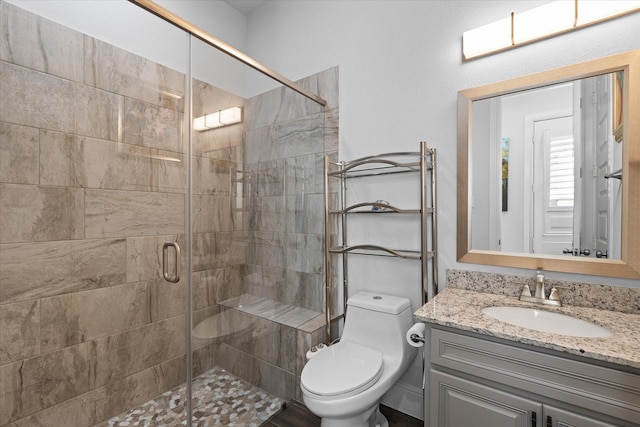 bathroom featuring vanity, toilet, and a shower with shower door