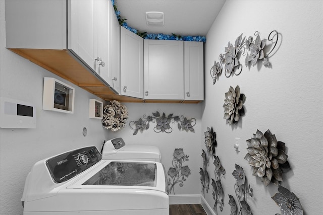 clothes washing area featuring cabinets, wood-type flooring, and washer and clothes dryer