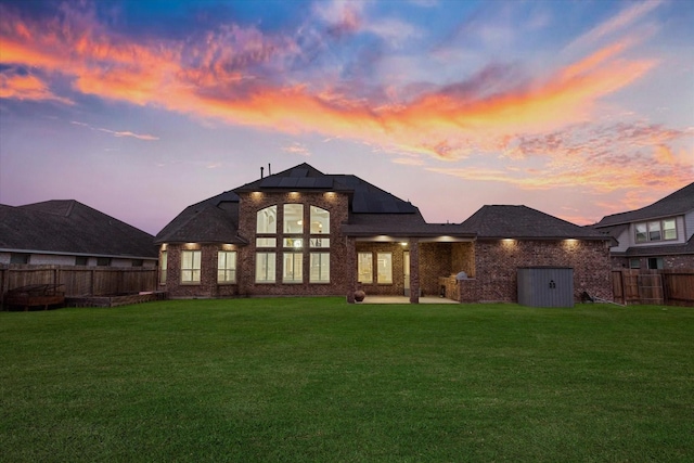 back house at dusk with a lawn