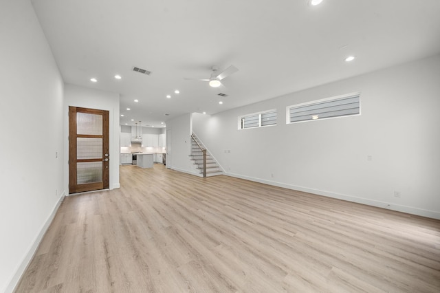 unfurnished living room featuring ceiling fan and light wood-type flooring