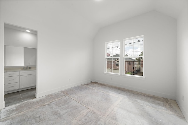 unfurnished bedroom with sink, vaulted ceiling, and ensuite bathroom