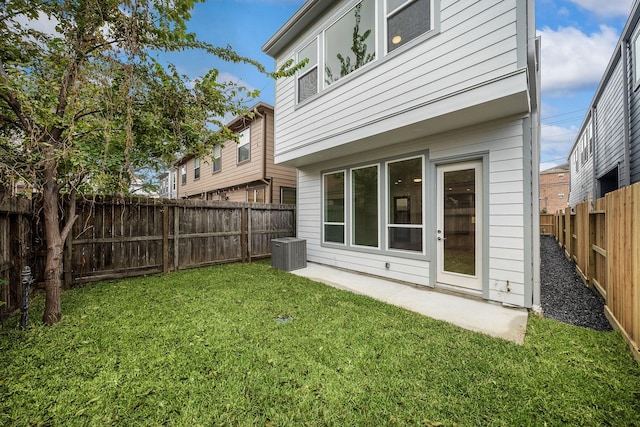 rear view of house with central AC unit and a lawn