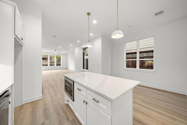 kitchen with ceiling fan, hanging light fixtures, white cabinets, built in microwave, and stainless steel dishwasher