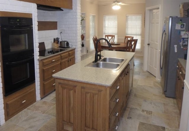 kitchen featuring sink, decorative backsplash, a kitchen island with sink, ceiling fan, and black appliances