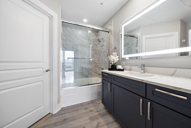 bathroom with enclosed tub / shower combo, hardwood / wood-style floors, and vanity