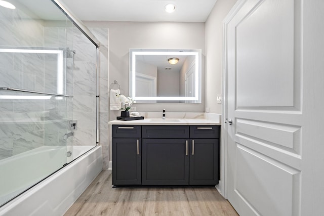 bathroom featuring vanity, hardwood / wood-style floors, and enclosed tub / shower combo