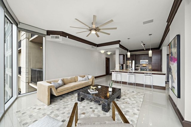 tiled living room featuring crown molding and ceiling fan