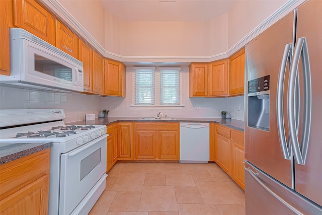 kitchen featuring tasteful backsplash, sink, light tile patterned floors, and white appliances