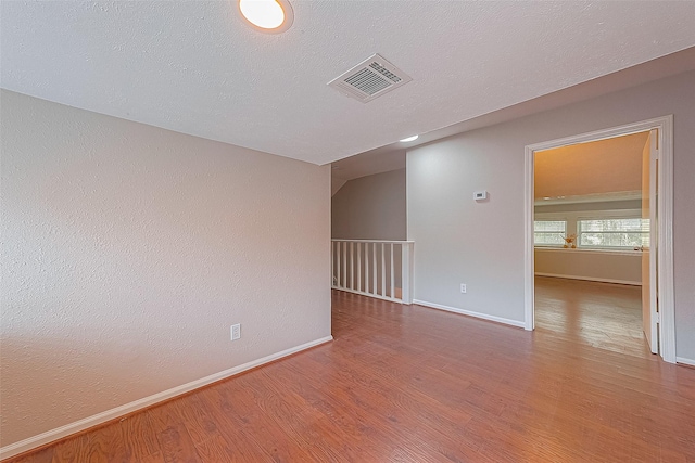 empty room with hardwood / wood-style flooring and a textured ceiling