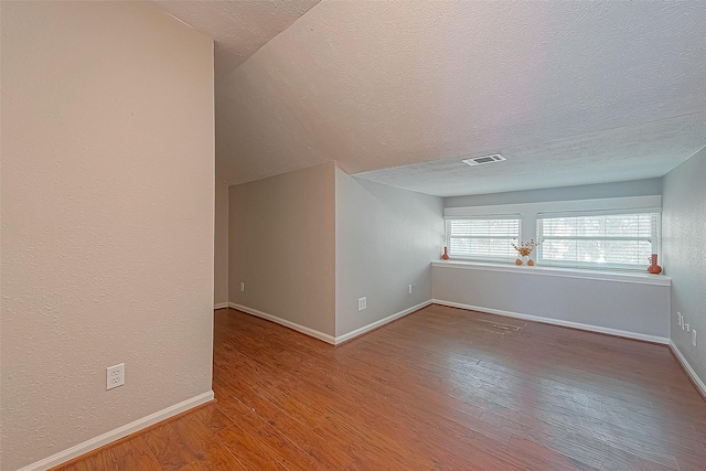 additional living space with hardwood / wood-style floors and a textured ceiling