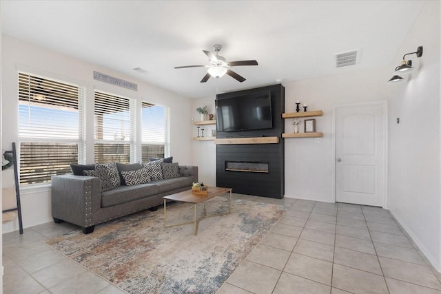 living room featuring a large fireplace, light tile patterned floors, and ceiling fan