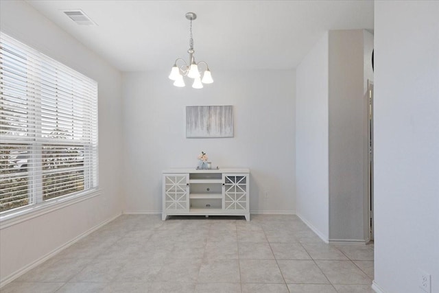 empty room with light tile patterned flooring and a chandelier