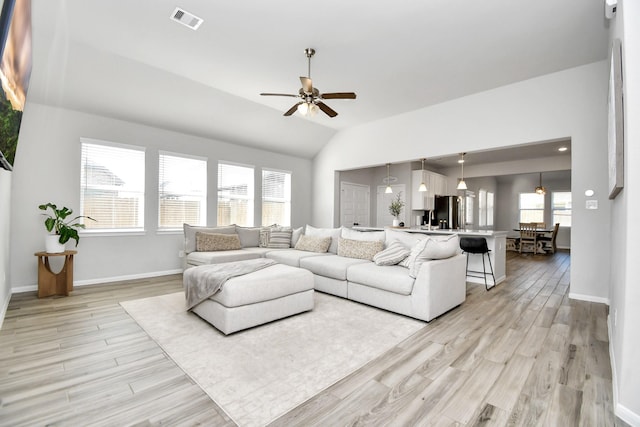 living room featuring ceiling fan, vaulted ceiling, and light wood-type flooring