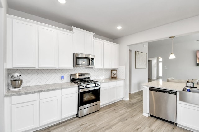 kitchen featuring hanging light fixtures, white cabinetry, appliances with stainless steel finishes, and backsplash