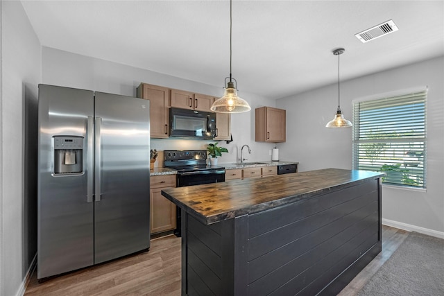 kitchen featuring pendant lighting, sink, butcher block counters, black appliances, and light wood-type flooring