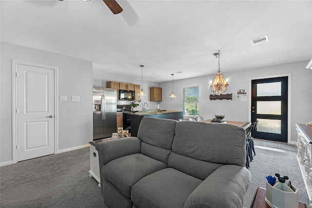 carpeted living room featuring sink and ceiling fan with notable chandelier