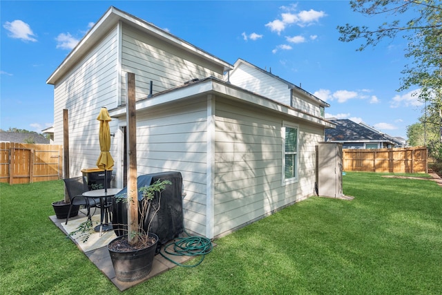 view of side of property featuring a lawn and a patio