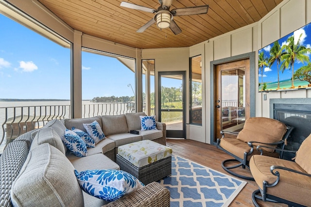 sunroom with exterior fireplace, wood ceiling, ceiling fan, and a water view