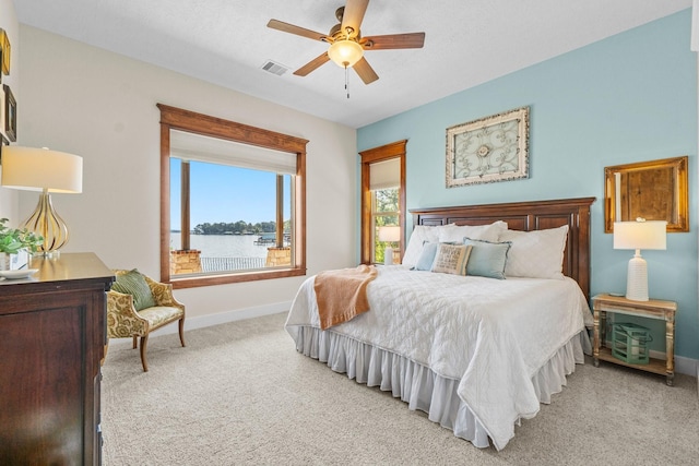 carpeted bedroom with a water view and ceiling fan