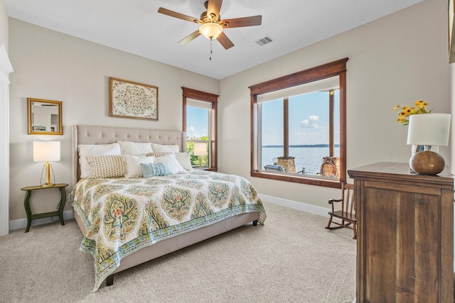 carpeted bedroom with a water view and ceiling fan