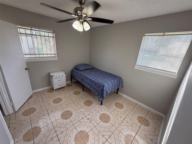 bedroom featuring ceiling fan, light tile patterned floors, and a textured ceiling