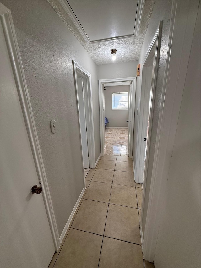 hall with light tile patterned floors and a textured ceiling