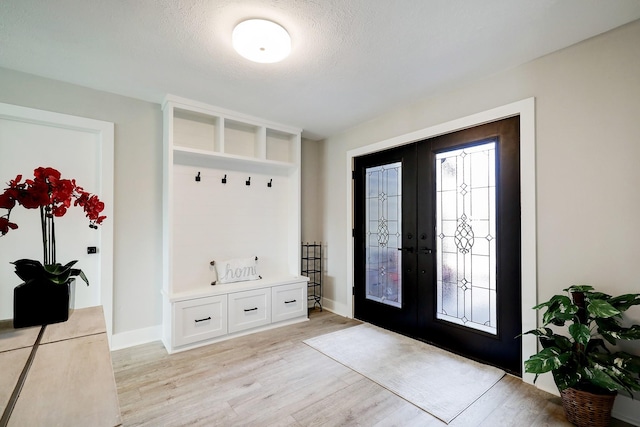 mudroom featuring french doors, light hardwood / wood-style floors, and a textured ceiling