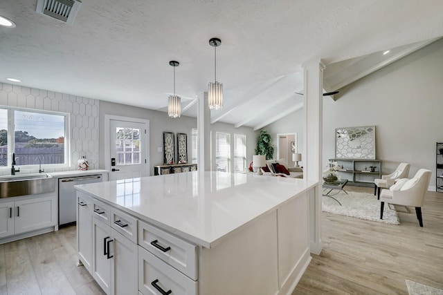 kitchen featuring sink, white cabinetry, lofted ceiling with beams, stainless steel dishwasher, and pendant lighting