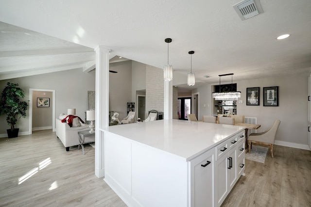 kitchen featuring ornate columns, white cabinetry, vaulted ceiling with beams, hanging light fixtures, and a kitchen island