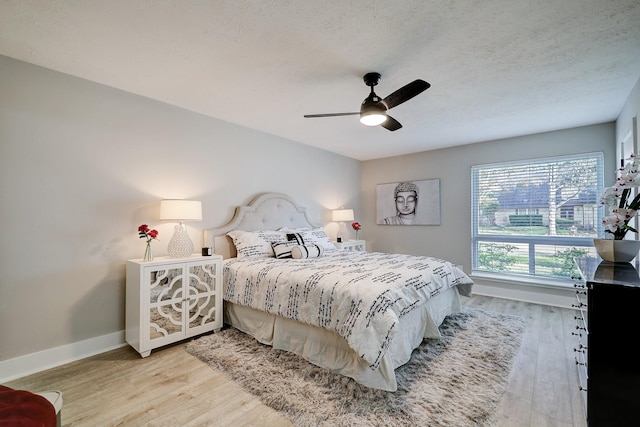 bedroom featuring ceiling fan, a textured ceiling, and light wood-type flooring