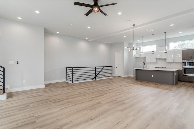 unfurnished living room with sink, light hardwood / wood-style floors, and ceiling fan