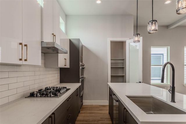 kitchen with appliances with stainless steel finishes, sink, white cabinets, and decorative light fixtures