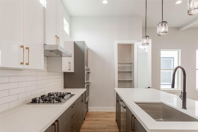 kitchen featuring decorative light fixtures, white cabinetry, sink, decorative backsplash, and stainless steel appliances