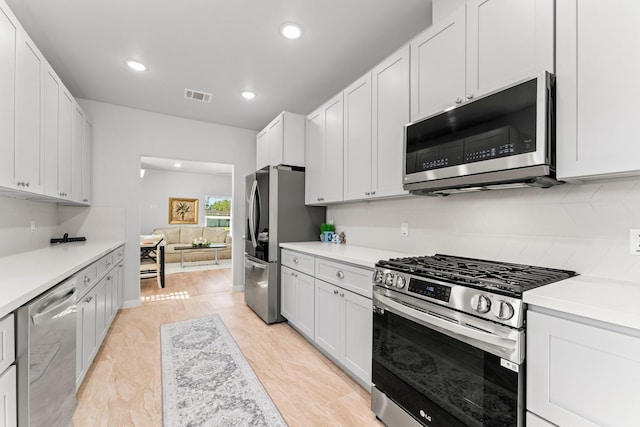 kitchen featuring stainless steel appliances, white cabinets, and backsplash