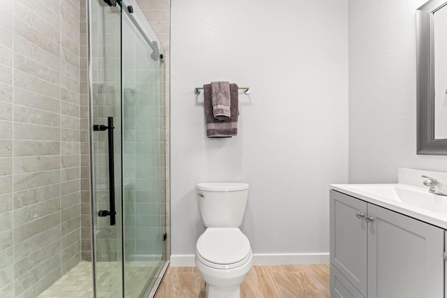 bathroom featuring vanity, a shower with door, and toilet