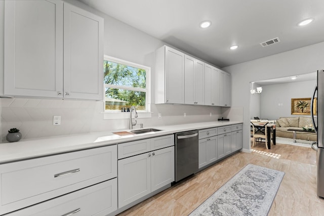 kitchen with appliances with stainless steel finishes, a chandelier, sink, and backsplash