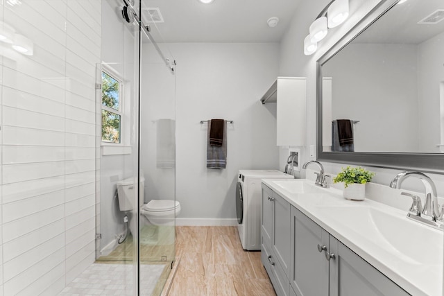 bathroom featuring vanity, toilet, separate washer and dryer, and a shower with door