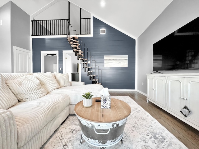 living room featuring dark wood-type flooring, high vaulted ceiling, and wooden walls