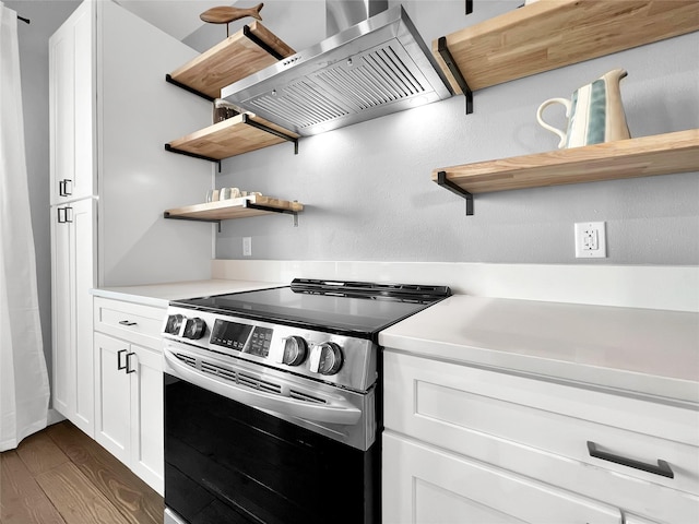 kitchen with stainless steel range with electric stovetop, wall chimney exhaust hood, dark hardwood / wood-style floors, and white cabinets