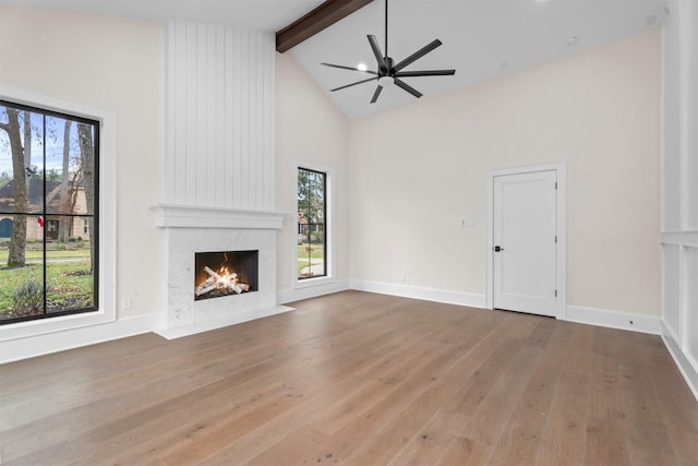 unfurnished living room with high vaulted ceiling, wood-type flooring, ceiling fan, a premium fireplace, and beam ceiling