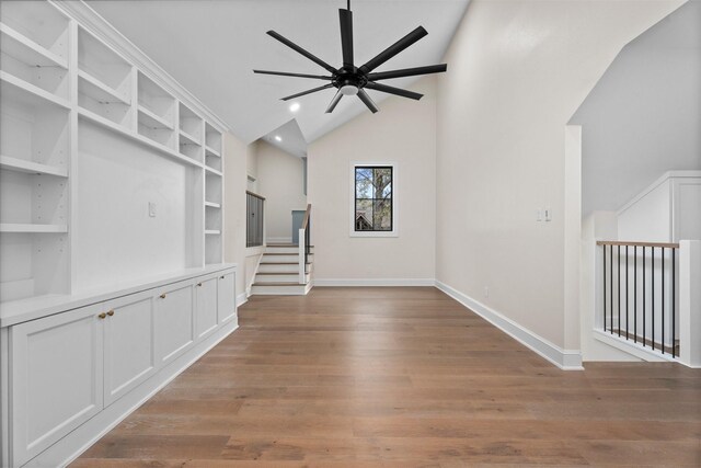 unfurnished living room with ceiling fan, high vaulted ceiling, light wood-type flooring, and built in shelves