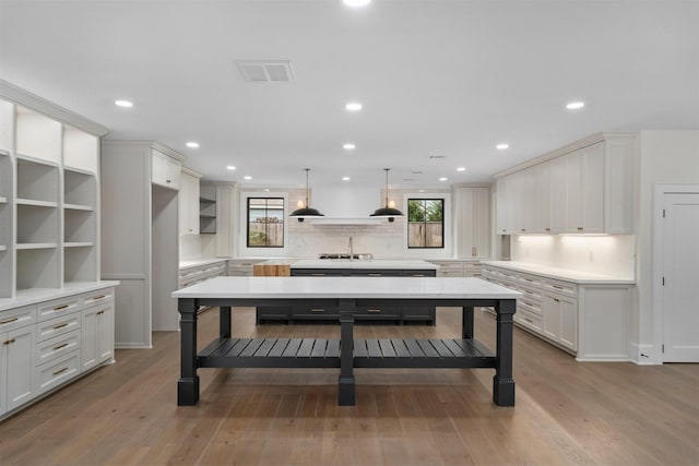 kitchen featuring hanging light fixtures, plenty of natural light, a center island, and white cabinets