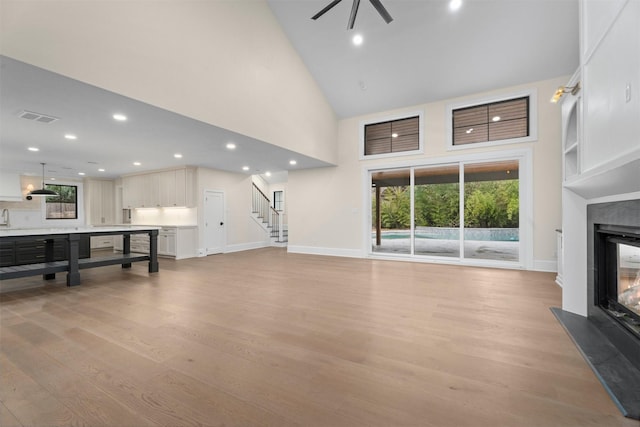 living room with ceiling fan, high vaulted ceiling, a wealth of natural light, and light hardwood / wood-style floors