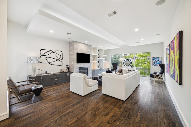 living room featuring dark hardwood / wood-style flooring, built in shelves, and a fireplace