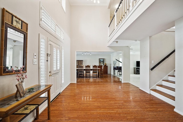 entryway with hardwood / wood-style flooring, ornamental molding, and a high ceiling