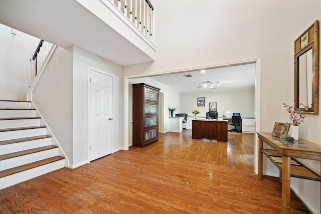 foyer entrance with a towering ceiling, wood-type flooring, and ornamental molding